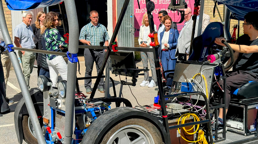 människor utomhus runt en bil med öppna sidor